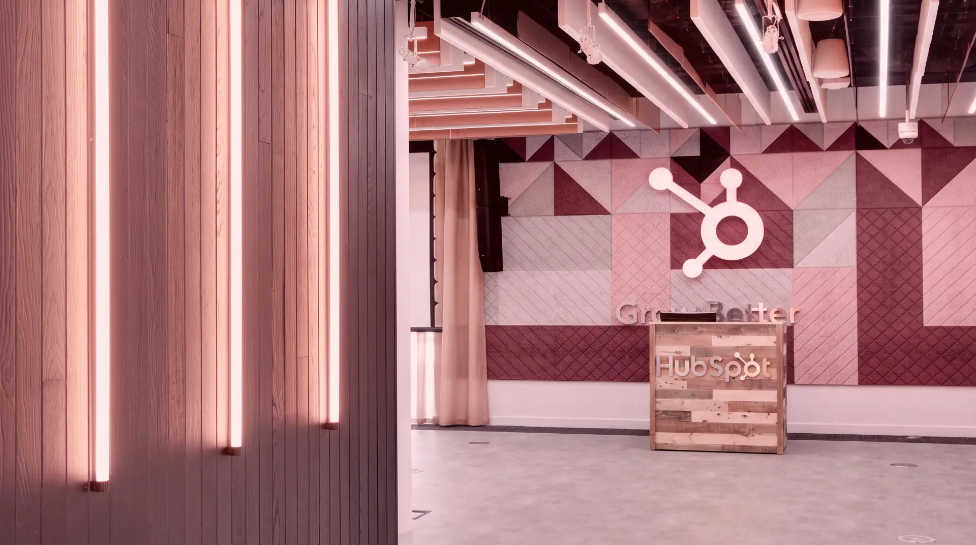 HubSpot office reception with an illuminated sprocket logo and the words Grow Better on the wall