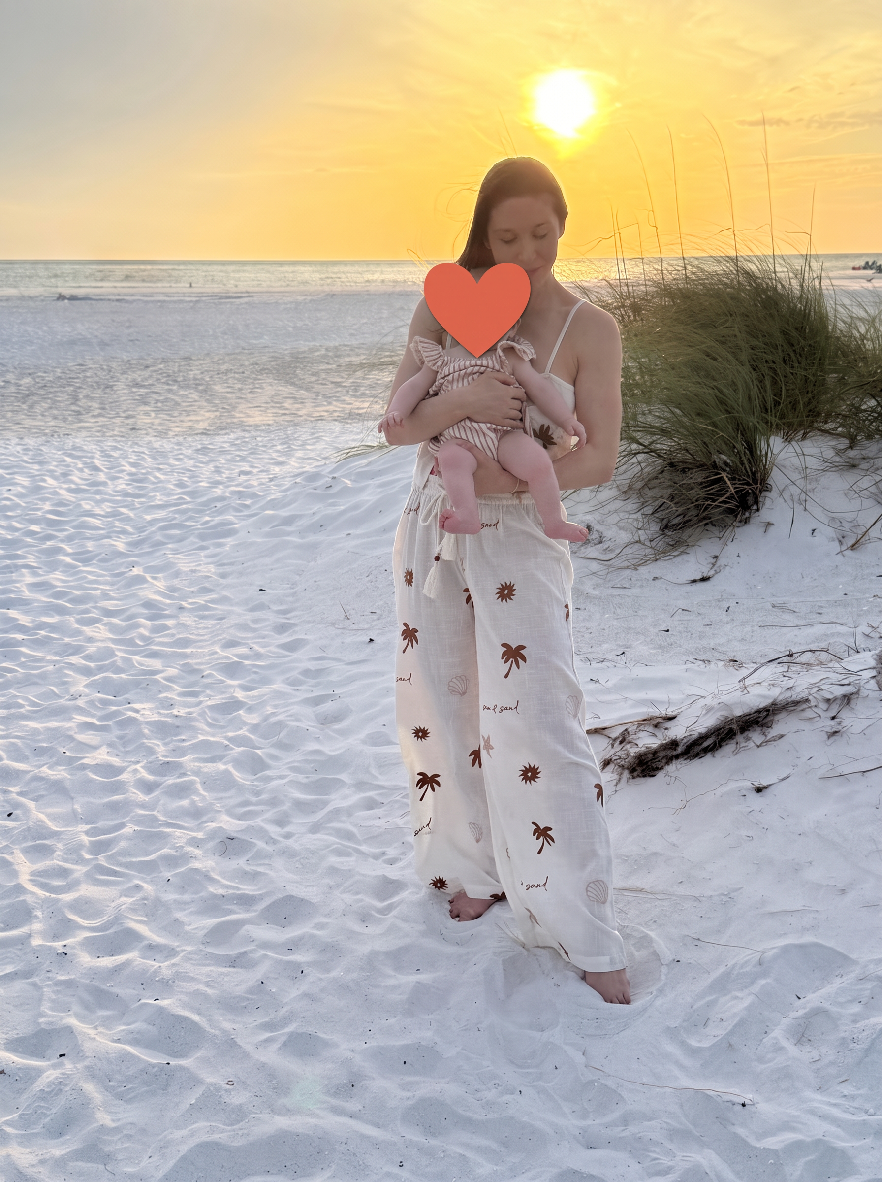 Lindsay Burke holding a baby on a beach at sunset